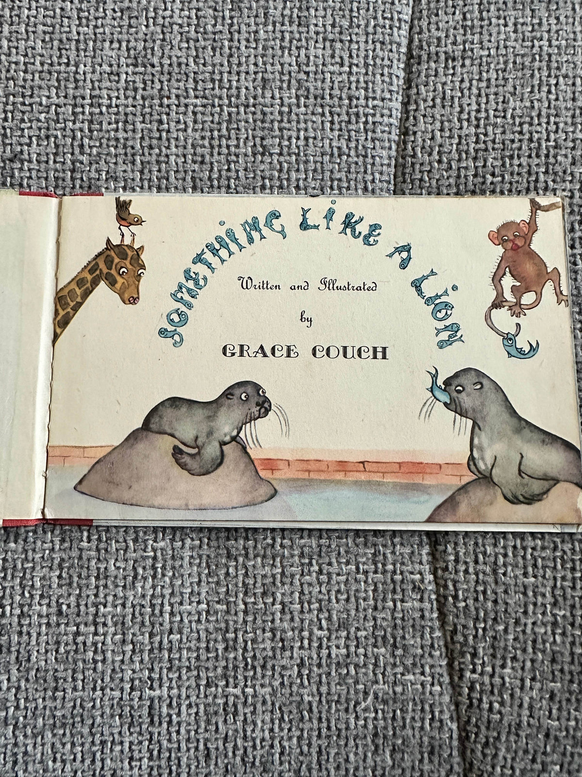 Something Like A Lion vintage children's book cover featuring seals, a monkey, and a giraffe