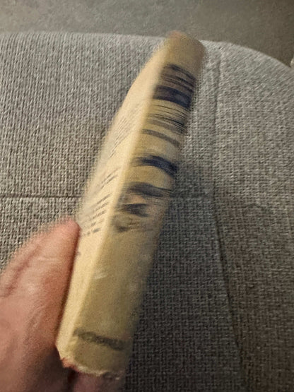Side view of 1953 A Thousand Witnesses first edition book with worn edges on a textured surface