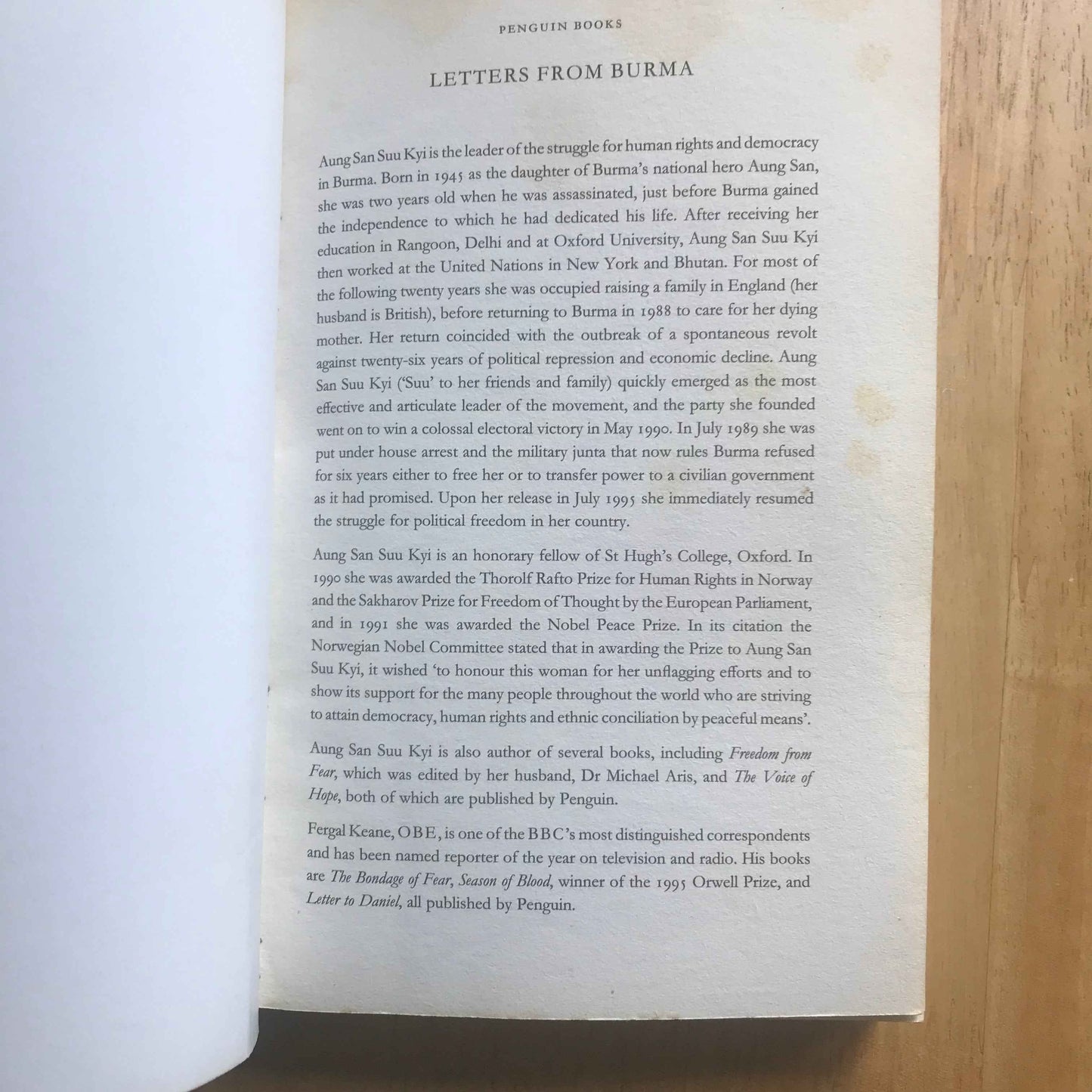 Open paperback showing title page and introduction text of Letters from Burma Aung San Suu Kyi book on wooden table