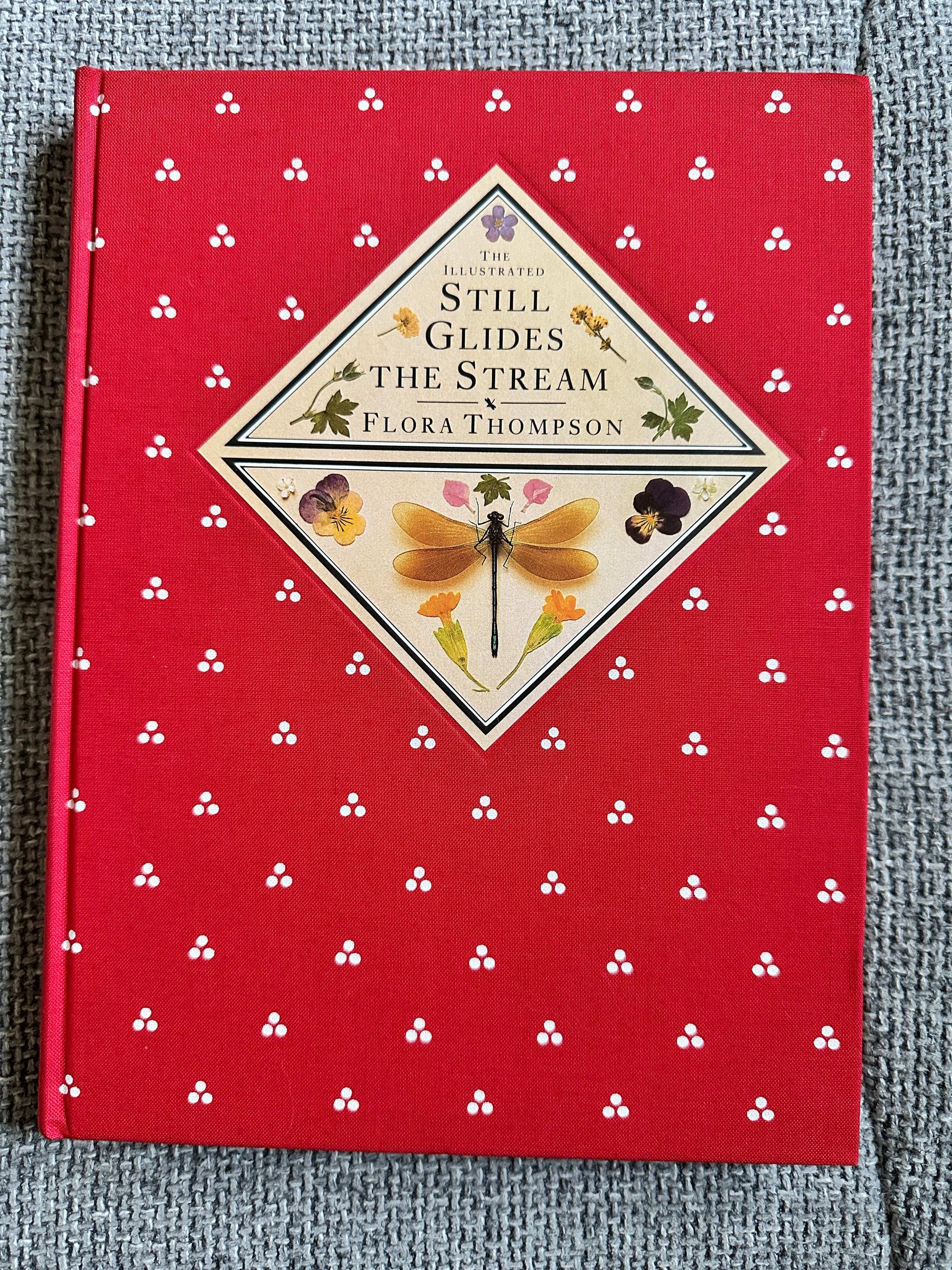 The illustrated edition of Still Glides The Stream Flora Thompson with a red floral cover design